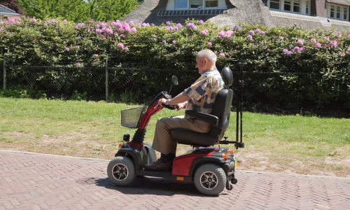 Pflegekraft unterstützt Seniorin beim Aufstehen und Gehen