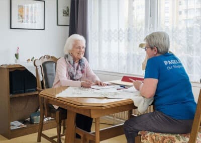 Pflegekraft und Bewohnerin sitzen gemeinsam am Tisch