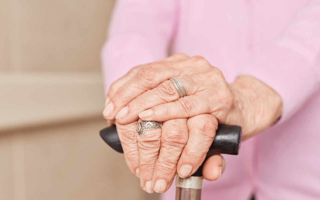 Hände einer Seniorin, welche einen Gehstock halten